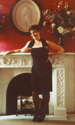 [Karin in a black cocktail dress in 
front of the white marble fireplace in Glen Park's Red Parlor, 
July 1999]