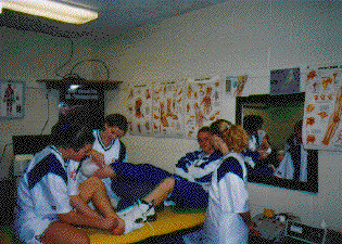 Women's basketball players talk to a teammate receiving treatment