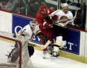 Hirsch, a Red Wing player and Lumme, all behind net
