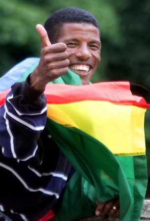 Ethiopian 10,000-meter star Haile Gebrselassie wears his country's flag, at the Ethiopian embassy in London, Wednesday August 2, 2000. The Olympic, and four-time World 10,000-meter Champion, who also holds the 10,000-meter and 5,000-meter world records, is in London to take part in a track meeting at Crystal Palace. (AP Photo/Max Nash)