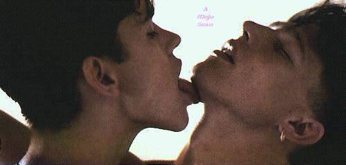 Two men, one licking the others chin.