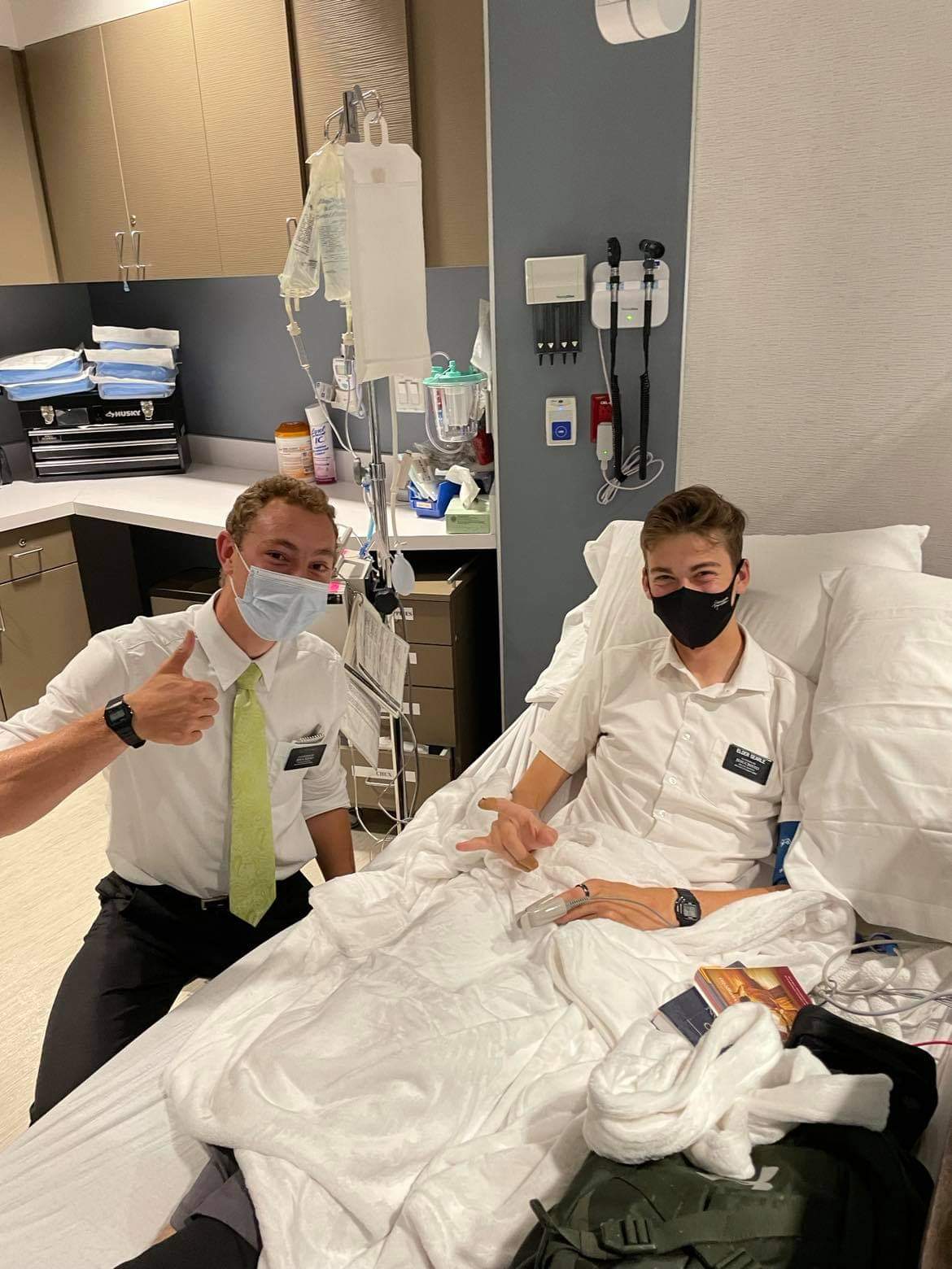 Two young men, one in hospital bed