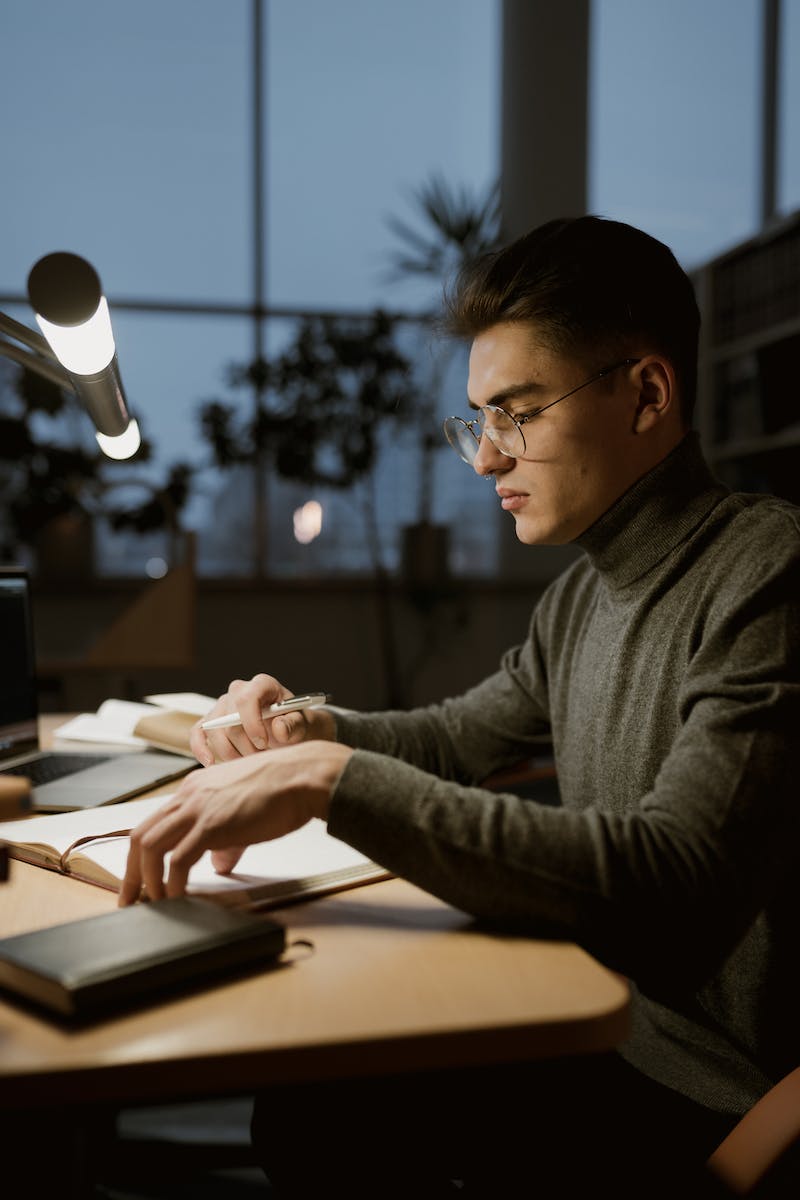 College aged man studying at night under lamp
