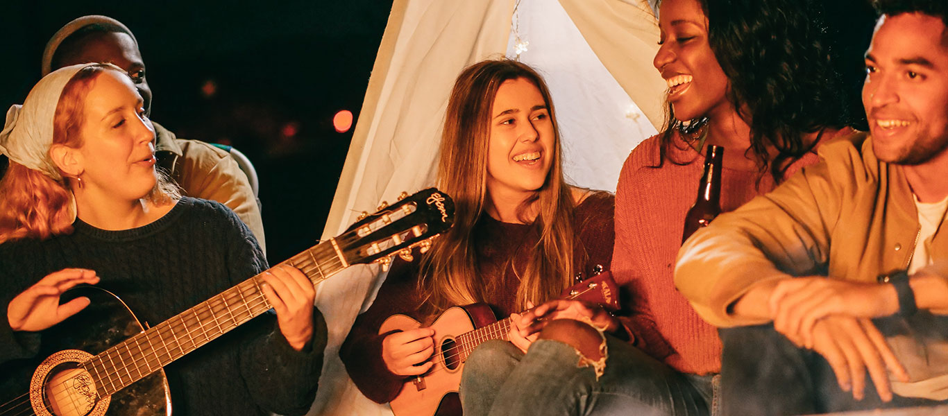 Friends singing in front of camp fire