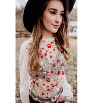 A white blouse embroidered with white and red flowers.