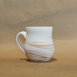 A bisque fired mug thrown with marbled clay