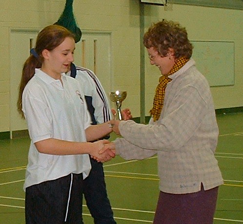 Winning captain Carys Webster collects the county indoor u13 cricket champions trophey from Bucks U15 manager Eileen Powell.