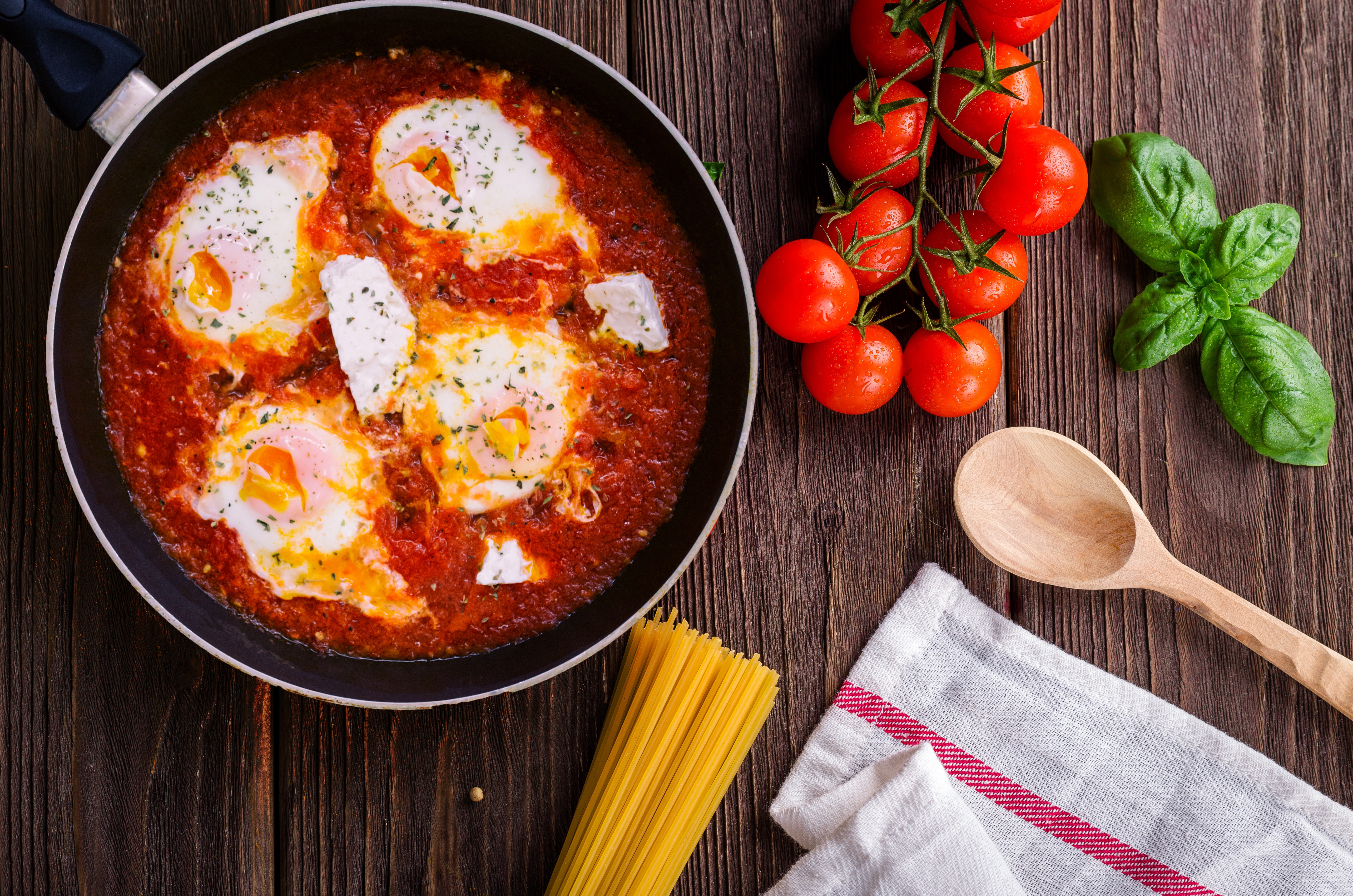 pasta dish with tomatos basil and wooden spoon image