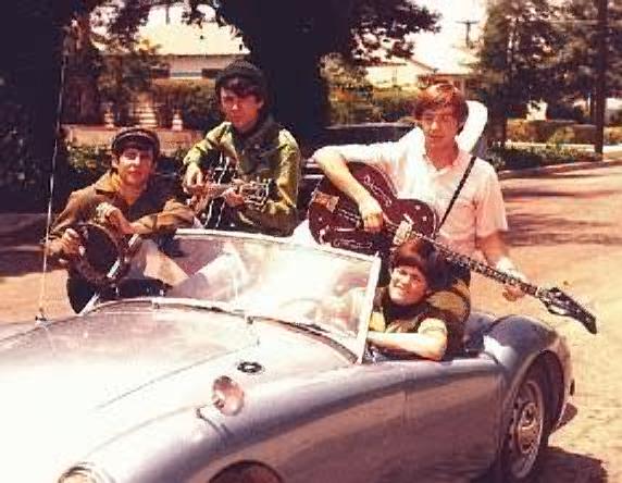 The Monkees playing their instruments in a car 