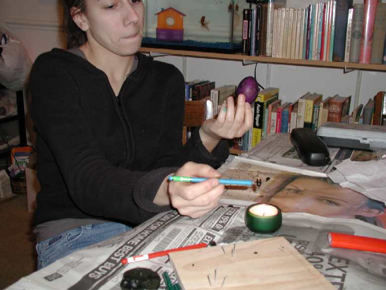 she's heating the kistka (pen) over the flame to keep the wax melty