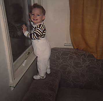 Infant Craig leaning against window