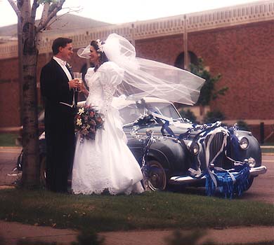 May 1991 - Craig and Kimberly toasting in front of blue classic car at their wedding