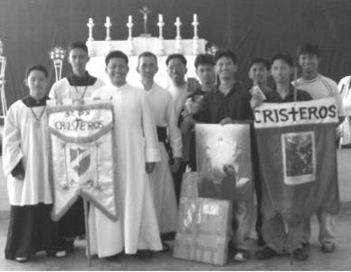 The happy Cristeros, with their chaplain, Fr. Soliman, and the District of Asia Superior, Fr. Couture, pose with their awards and pilgrim banners.