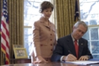 12/19/06: Laura Bush stands by President George W. Bush as he signs S. 843, the Combating Autism Act of 2006, in the Oval Office Tuesday, Dec. 19, 2006.&nbsp; "For the millions of Americans whose lives are affected by autism, today is a day of hope ..." - President George W. Bush, 12/19/06