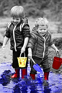 Black and white photo of two boys palying in puccle with some features colorized