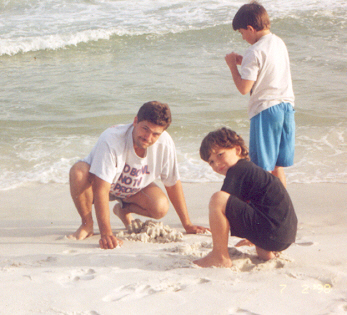 Jerry, James and Joshua digging in the sand near the edge of the ocean