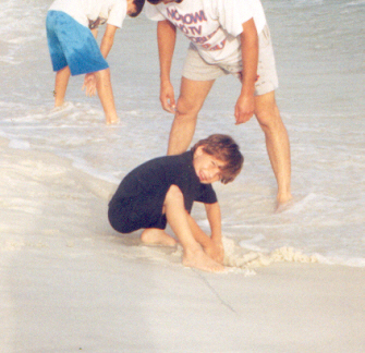 Jerry, James and Joshua digging in the sand near the edge of the ocean