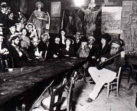 Inside the Lapin Agile.  Fr�d� is sitting on the right with a guitar; on the wall to the left of the large crucifix is the Picasso painting "Au Lapin Agile."