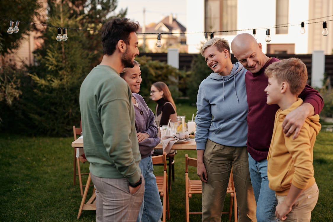 family and friends in a back yard having dinner together.