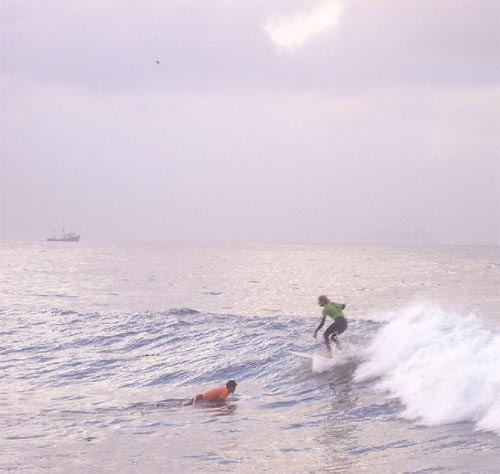 Green rider turns on a wave.Surfing for a for a long ride on this wave.