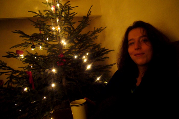 Marion with a hot drink, looking very content beside the Krismas tree.
