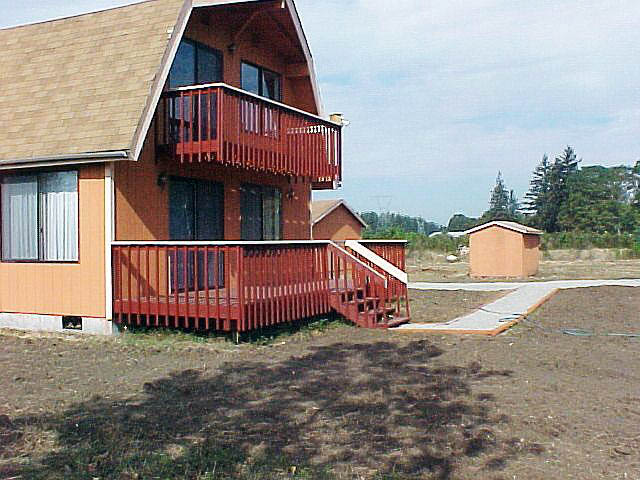 House side view with garage and storage shed in background