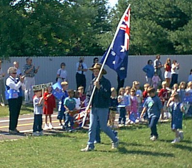 Darryl carrying the Australian flag, kids in tow.