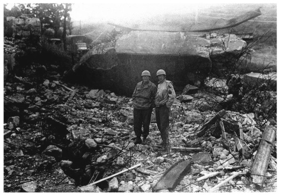 Two soldiers survey destroyed German gun fortification