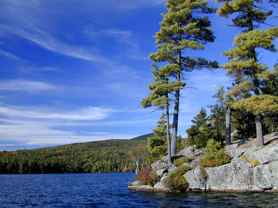 A rocky point sticking out into a lake with a view of a mountian in the background