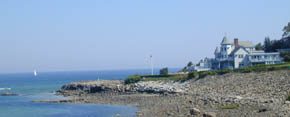 A classic Maine Inn overlooking the coast with a sail boat making way.