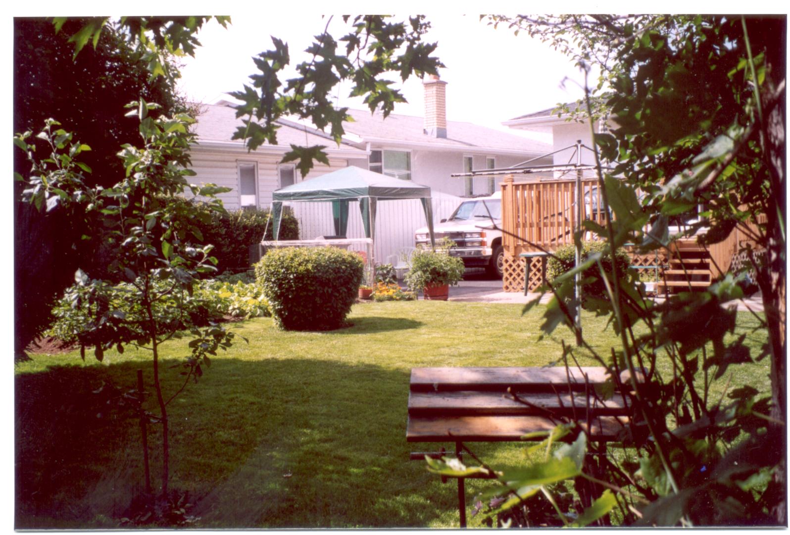 The back yard at 414 Cabot Court showing the lawn and garden, with a glimpse of the deck, taken in July 2003.