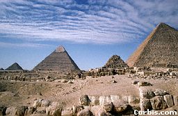 the pyramids of Giza against a blue Egyptian sky filled with stretchy clouds