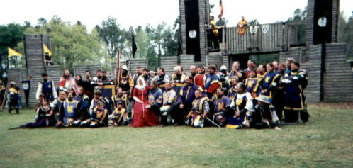 Calontir fighters assembled in front of a wooden castle