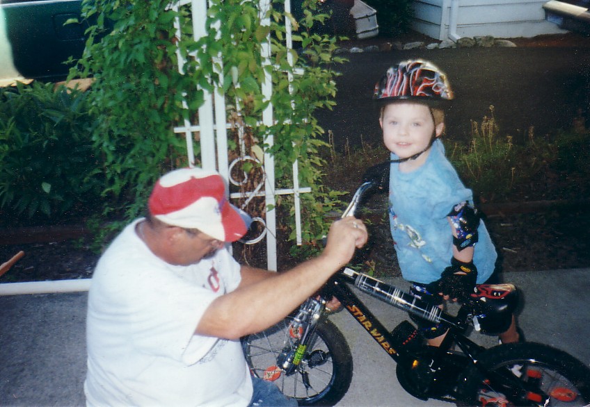 Grandpa fixing the wheels on William's new Darth Maul bike.&nbsp; August 2001