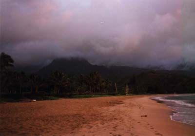 Photo of a dark mountain skyline capped with storm clouds rendered
pink by the final moments of dusk.
