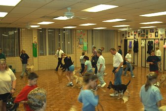 The pups are divided into two groups.  
Walking on leash in two circles, and going in 
opposite directions, they are learning to listen 
to and follow their master without being 
distracted by other pups and people.