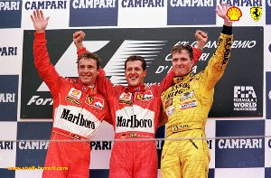 [IMAGE : Michael and Ralf Schumacher share the podium with Eddie Irvine at Monza]