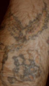 This is a teddy-bear sitting next to a skull with a burning candle and a phoenix being born from the candle flame. It is dedicated to my first son Jaroth who passed away at a very young age. It is on the back of my left forearm.