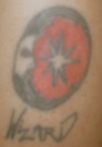 This is my first and only professionally done tat. It was my first tat, but I did design and draw it out. It was my logo and signature back in the days when I used to air-brush. It is located on my left shoulder.