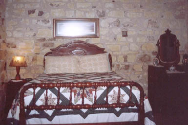 In the bedroom is a dresser and bed was handcrafted in Germany. Topped with a quilt, the bed sits fashionably high off the floor. An armoire for hanging clothes is an old family heirloom.