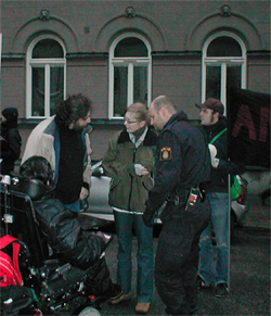 Tv� icke-funktionshindrade aktivister och en funktionshindrad aktivist i permobil talar med en polis.