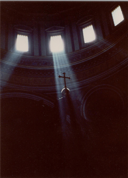 Light streaming in from windoes illuminates a cross.