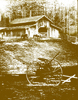 Barn with horses in front. Old plow in foreground