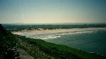 Saunton beach from the road above. Tide going out. The beach is bigger than it looks from here. Good surf break - that's what makes the sand hard.