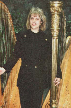 Lead Harpist standing by two harps