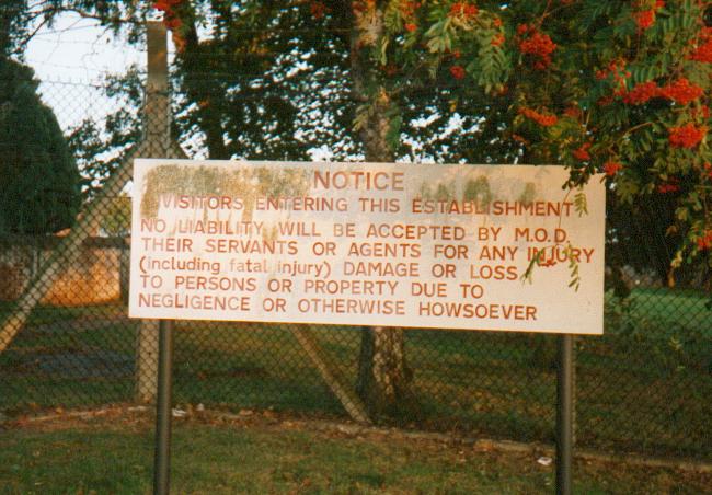 (c.1996) the legal speel sign, posted at the main gate to the camp (note fencing style, tree species as commom features of MOD sites)