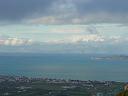 a view of modern day corinth with the ocean and snow covered mountains in the distance