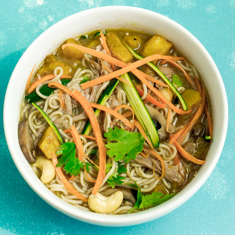 aisan noodle soup dish in a white bowl on a turquoise background