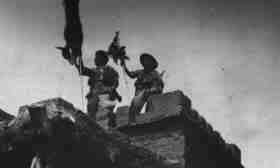 Two Italian soldiers hoist a friend flag over a hostile bunker in the British Somalia 