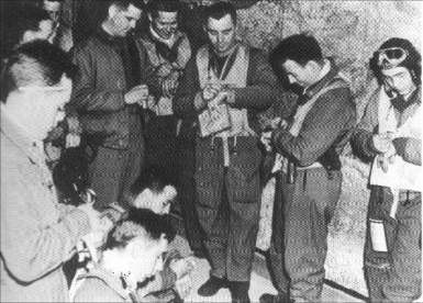 20th.FG pilots synchronize their watches after a mission briefing. Col. Cy Wilson is shown in the center, wearing the Mae West.
